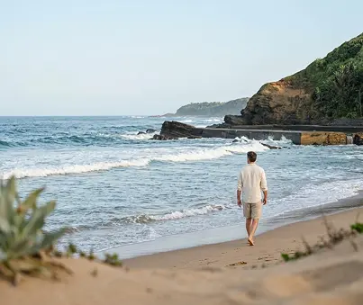 Man walking along Thompson’s Bay beach