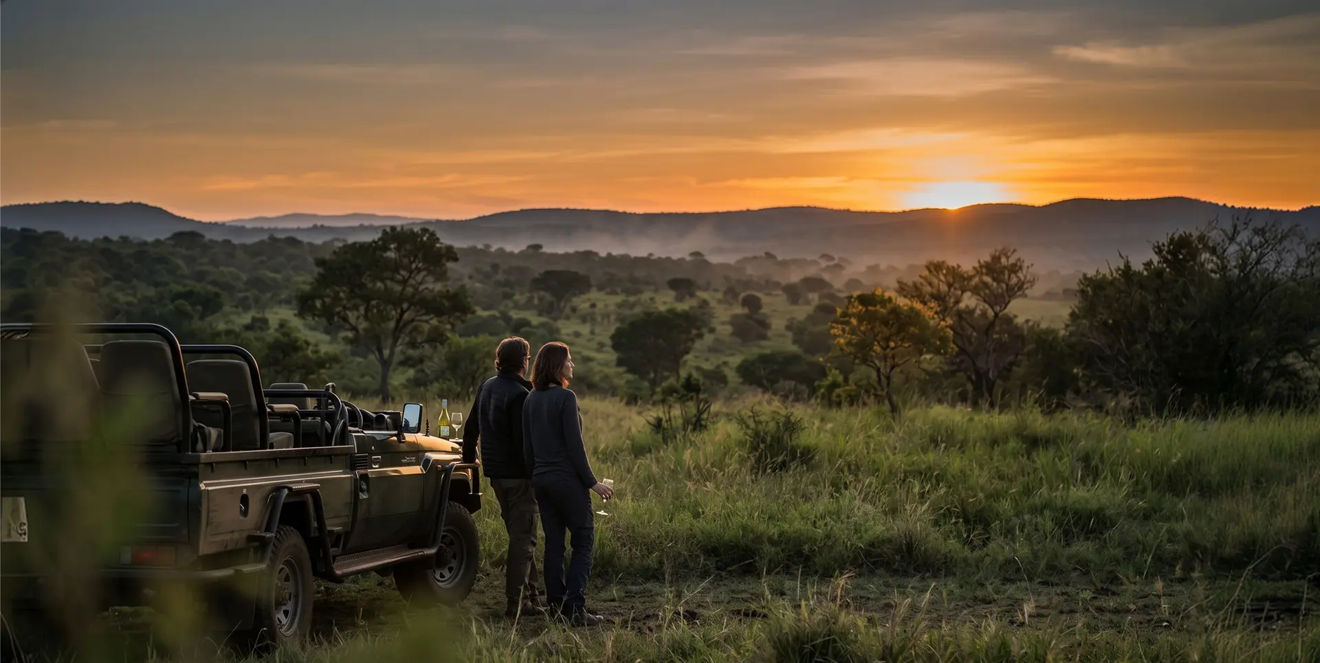 Couple watching the sunset beside a game-drive vehicle